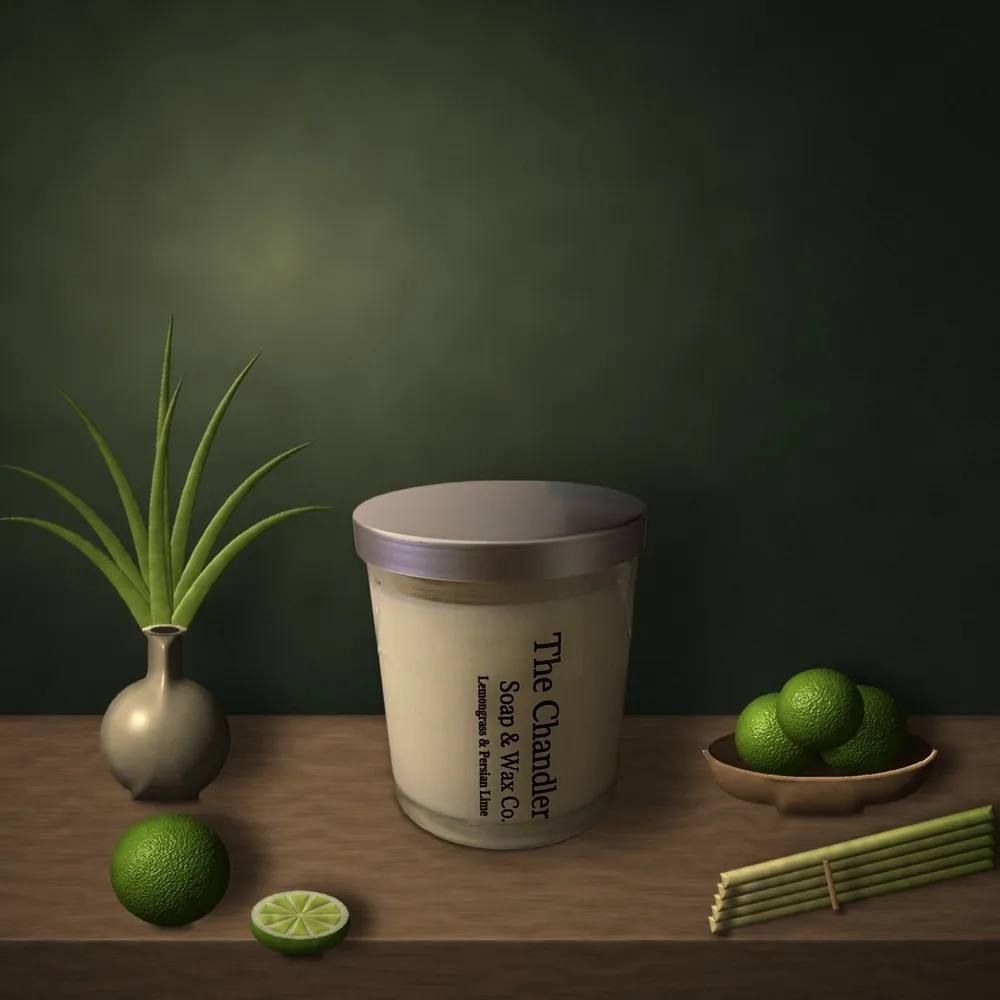 A Lemongrass & Persian Lime candle on a wooden table with limes and a vase of grass